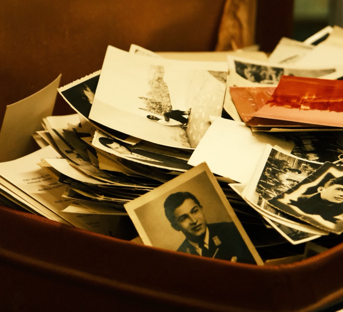 An old suitcase spilling over with black-and-white family photographs.
