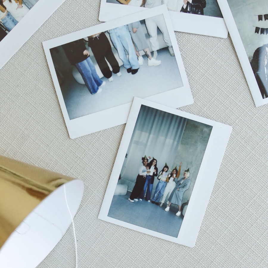 Instant prints scattered across a pale linen surface.