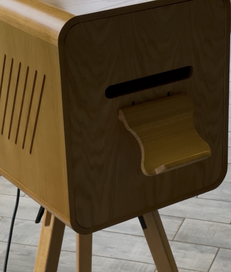 The printer stand, with the print slot and catch tray, set up indoors.
