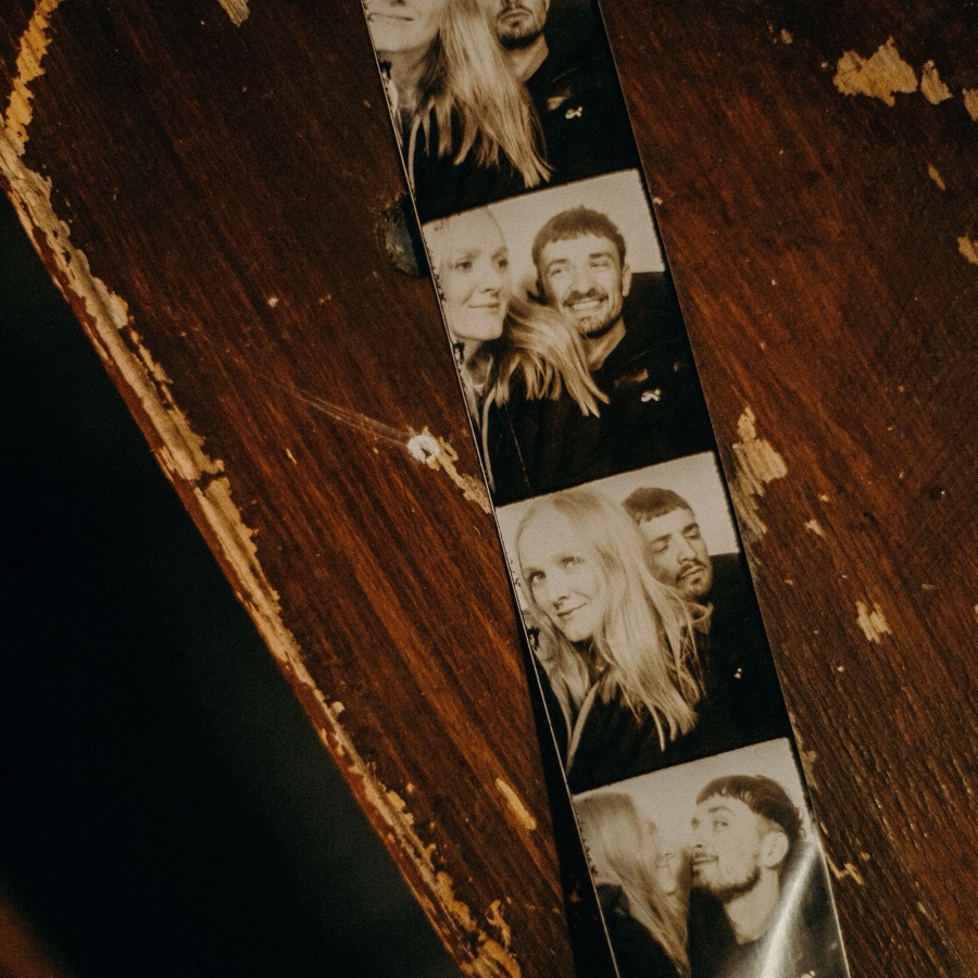 A black-and-white photo strip lying on a worn wooden table.